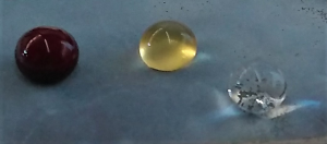 Picture showing, from left to right, a whole blood droplet, a blood plasma droplet, and a water droplet