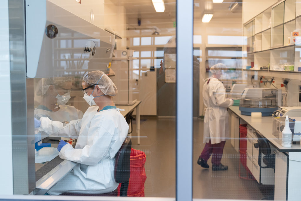 Two scientists in lab coats working in a laboratory with safety equipment and instruments.