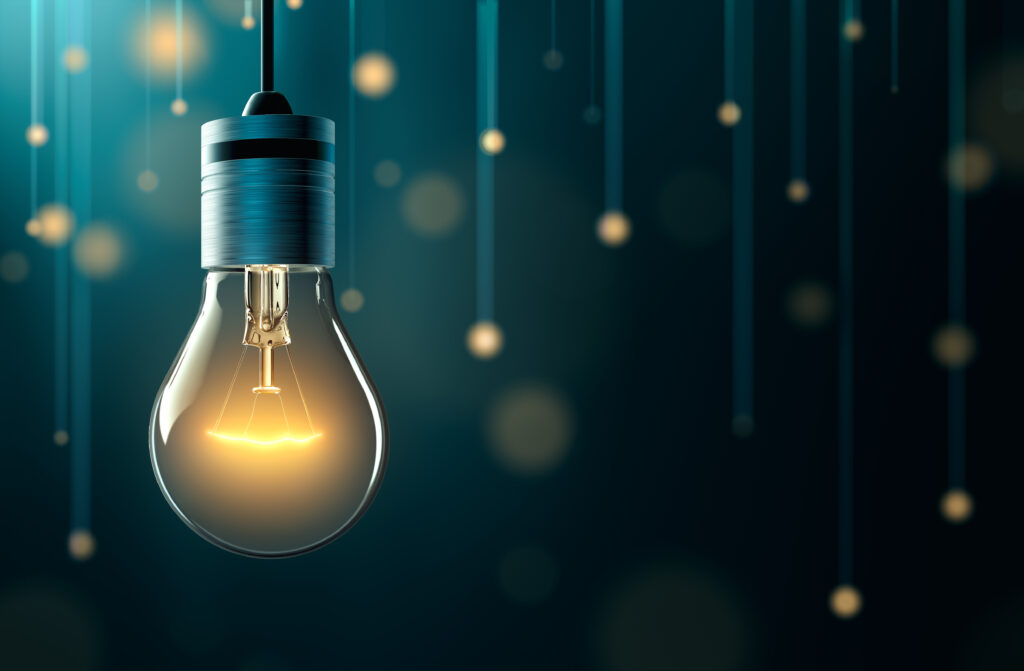 Illuminated light bulb hanging against a dark background with glowing orbs and vertical lines.
